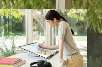 Una persona utilizza una Penna per Surface per scrivere sullo schermo di un dispositivo Surface Studio 2+ in un ufficio casalingo