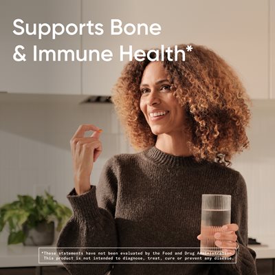 Hình ảnh một người phụ nữ mỉm cười cầm một ly nước và một viên D3K2 Plantgel với dòng chữ: "Hỗ trợ sức khỏe xương khớp và hệ miễn dịch.*" Và một chú thích ghi: "*Những tuyên bố này chưa được Cục Quản lý Thực phẩm và Dược phẩm Hoa Kỳ (FDA) đánh giá. Sản phẩm này không nhằm mục đích chẩn đoán, điều trị, chữa khỏi hoặc ngăn ngừa bất kỳ bệnh nào."