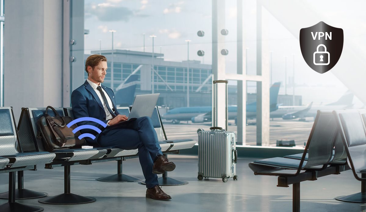 A businessman with the RT-AX50 Go router and suitcase by his side, sits in the airport using laptop, waiting for his flight.