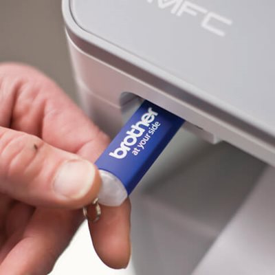 Close-up of person inserting USB drive into printer's USB port