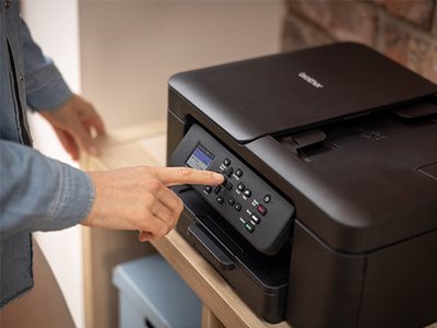 A woman operating a Brother DCP-J1360DW through the front control panel