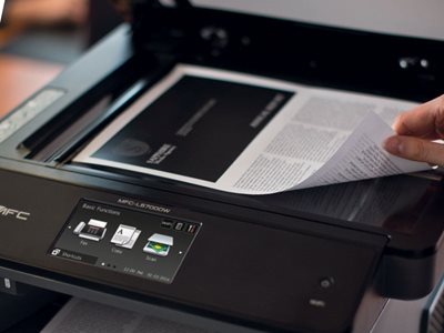 Person placing document on printer's flatbed scanner for scanning