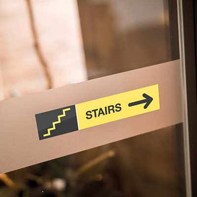 Yellow and black door sign reading "stairs" with stair icon and arrow
