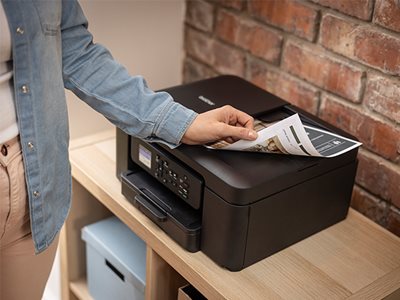 A woman removing print output from the Brother DCP-J1310DW