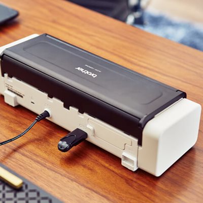 Closed scanner on desk, shown from the back, with USB drive plugged in