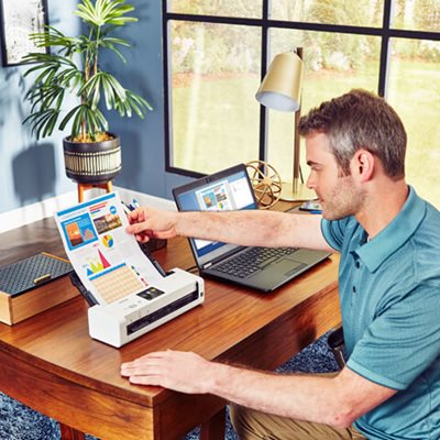 Man sitting at desk, using the automatic document feeder to scan a multi-page document with color