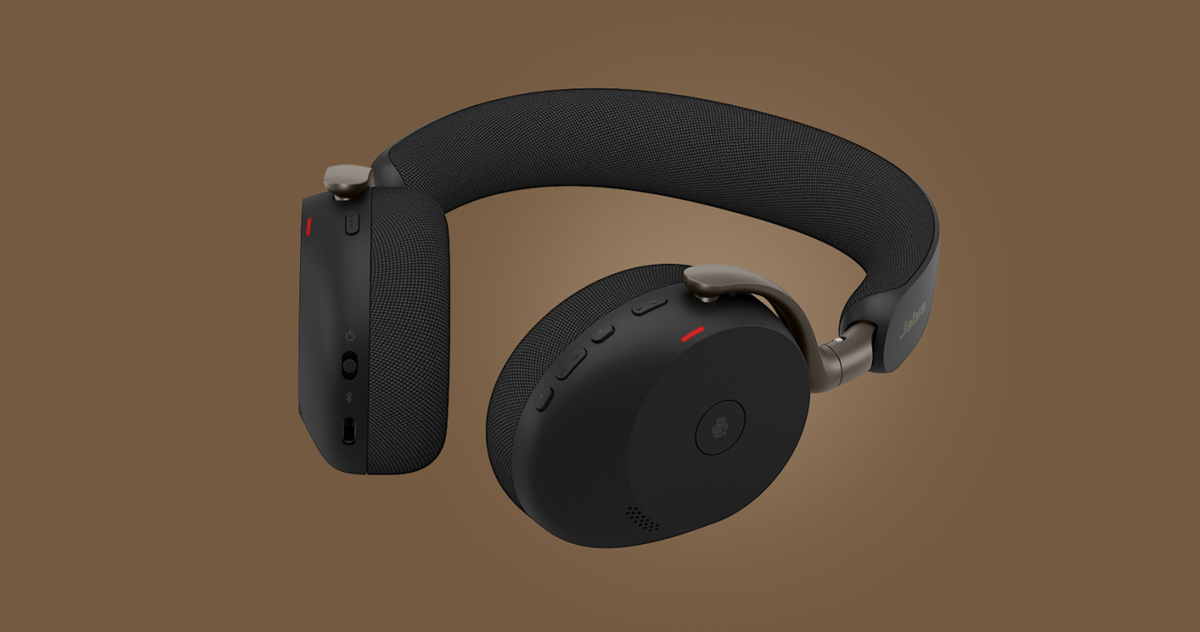 Side view of a black Jabra Evolve3 85 over‑ear headset against a brown background, showing the padded headband, earcup fabric texture, and physical control buttons.