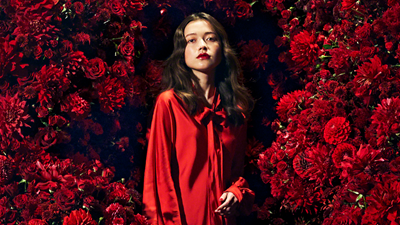 Portrait of a woman dressed in red, surrounded by red flowers