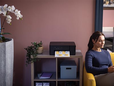 A woman sat next to a Brother DCP-J1260DW, on a shelving unit