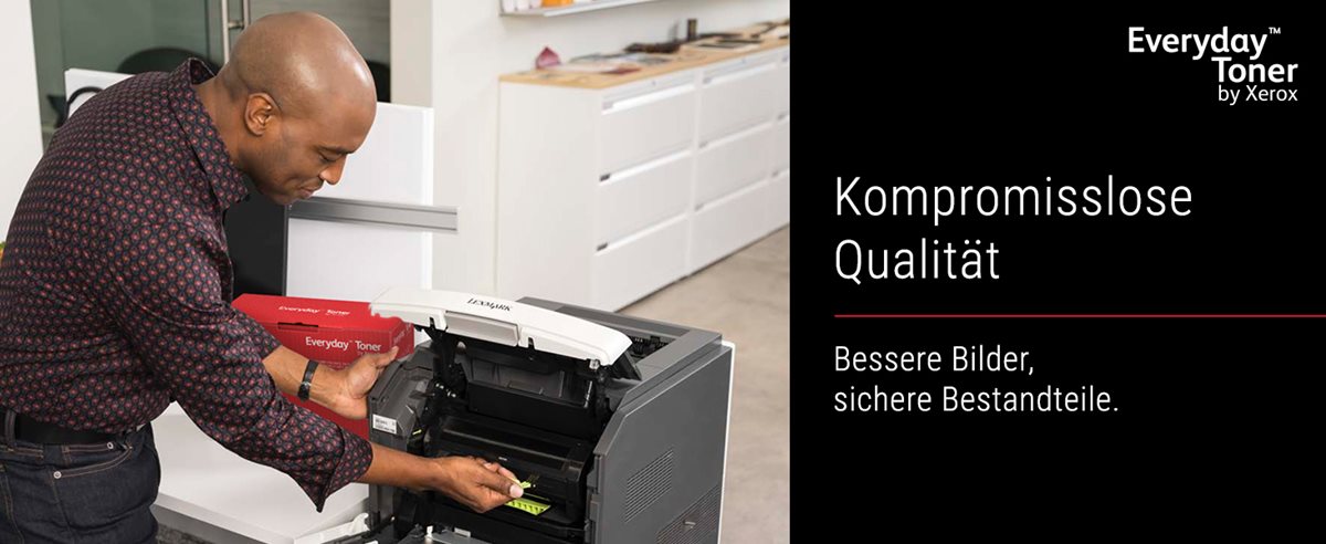 A man standing next to an HP printer on a desk, holding an Everyday Toner by Xerox cartridge in his right hand.