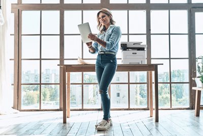 Female working on tablet in home office next to a Xerox B235 Printer.
