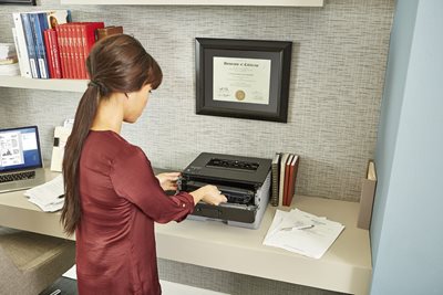 Woman at printing station, inserting replacement drum unit into laser printer