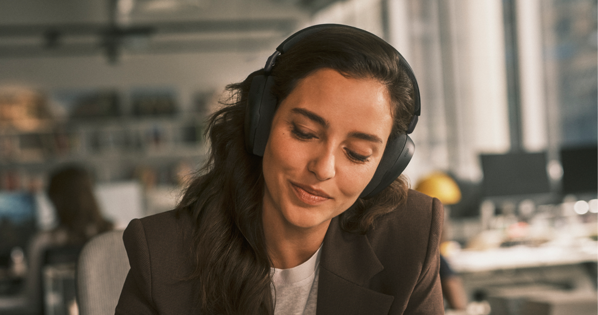 Close‑up of a woman wearing a Jabra Evolve3 headset while working in a modern office.