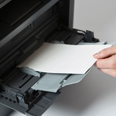 Person loading letter-size #10 blank envelopes face-up into multipurpose tray for printing