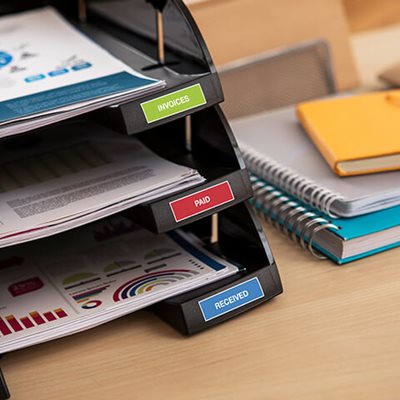 Printed labels on desktop paper tray, reading "invoices," "paid," and "received"