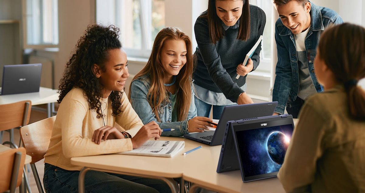 Group of students collaborating on a project using laptops in a classroom.