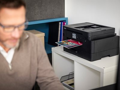 A Brother MFC-J4550DW on a shelving unit with print output