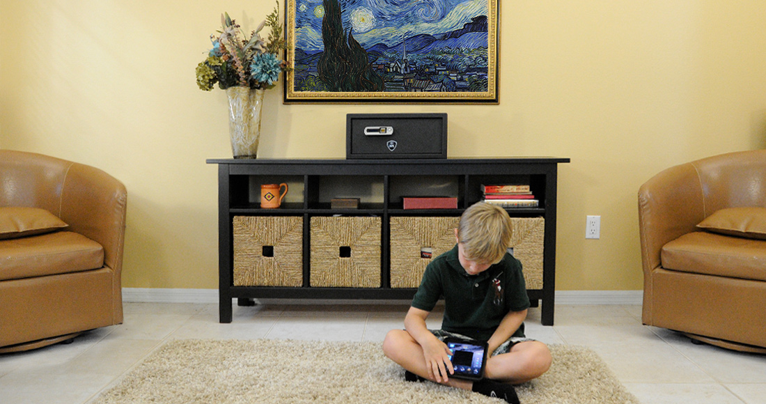 Boy sitting on the floor with the Verifi Smart Safe S6000 sitting on a table behind him