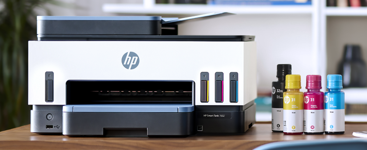 An HP Smart Tank 7602 printer with ink bottles on a desk.