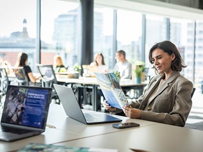 A woman looking at colour print output while sat at a desk in an office environment