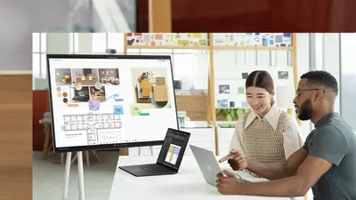 Two co-workers interact with two Surface Laptop 5 devices with a Hub 2S in the background