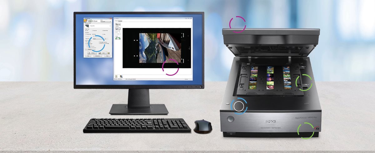 V850 photo scanner on a table next to a monitor, keyboard, and mouse