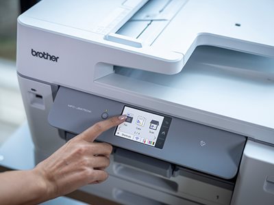 A woman operating a Brother MFC-J6975DW using the colour touchscreen