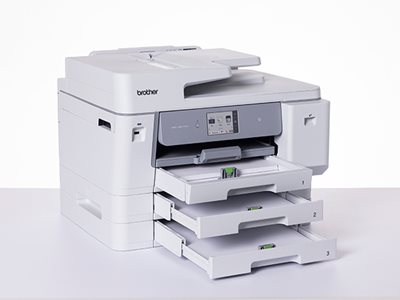 A Brother MFC-J6977DW on a light grey surface with paper trays open