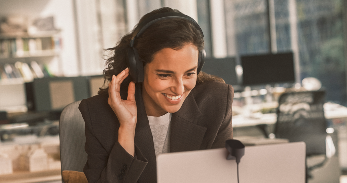 Close‑up of a woman wearing a Jabra Evolve3 headset while working in a modern office.