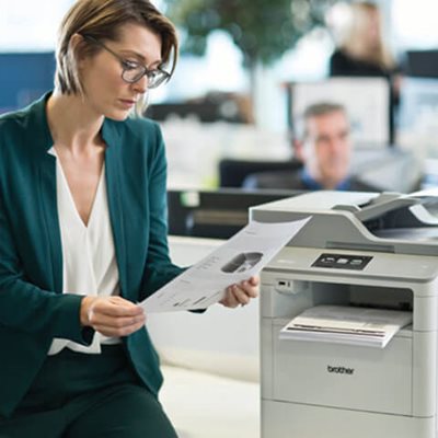 Woman reviewing printed documents at office printing station